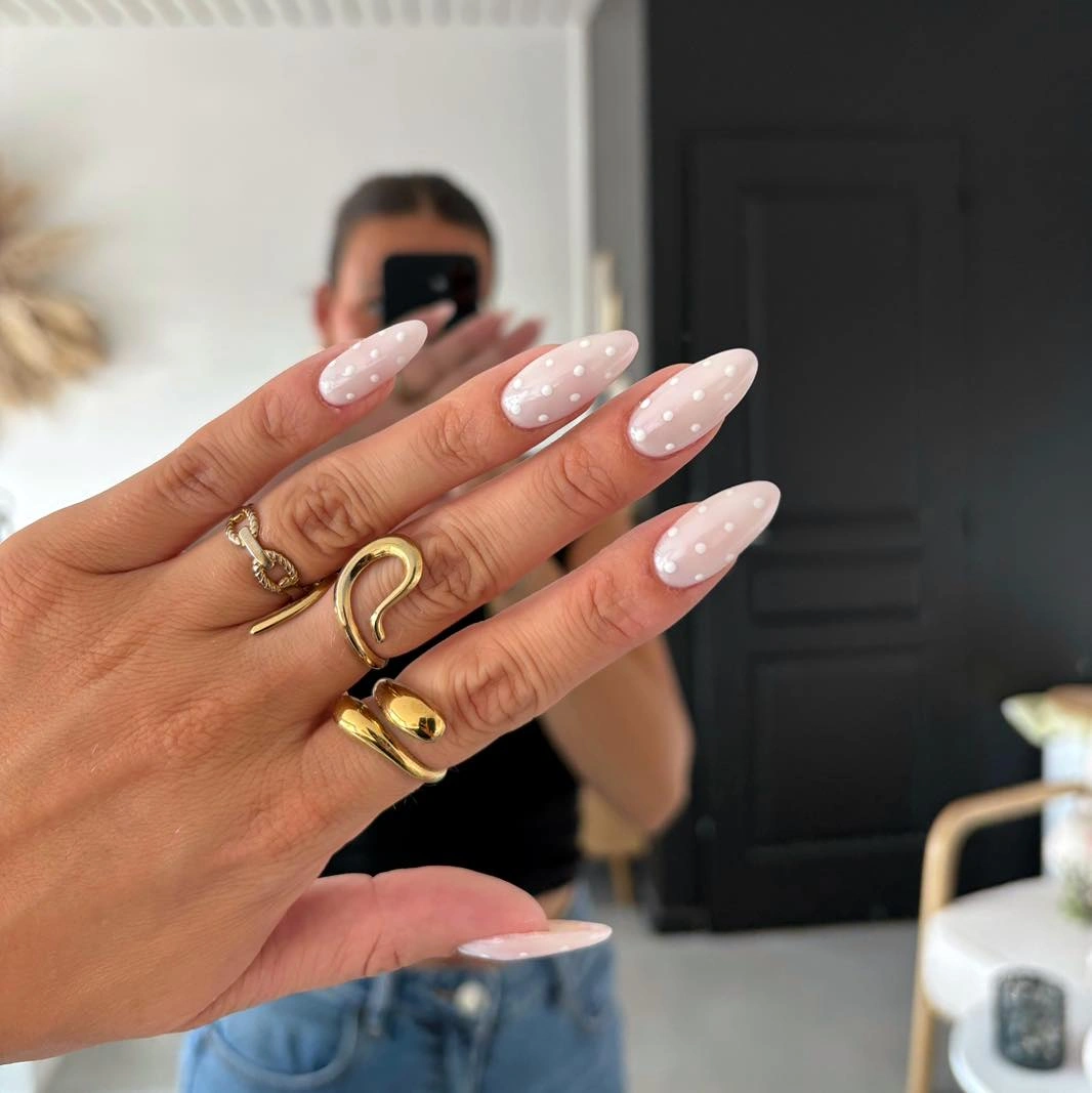 Long pale pink nails with white petal dots and floral accents