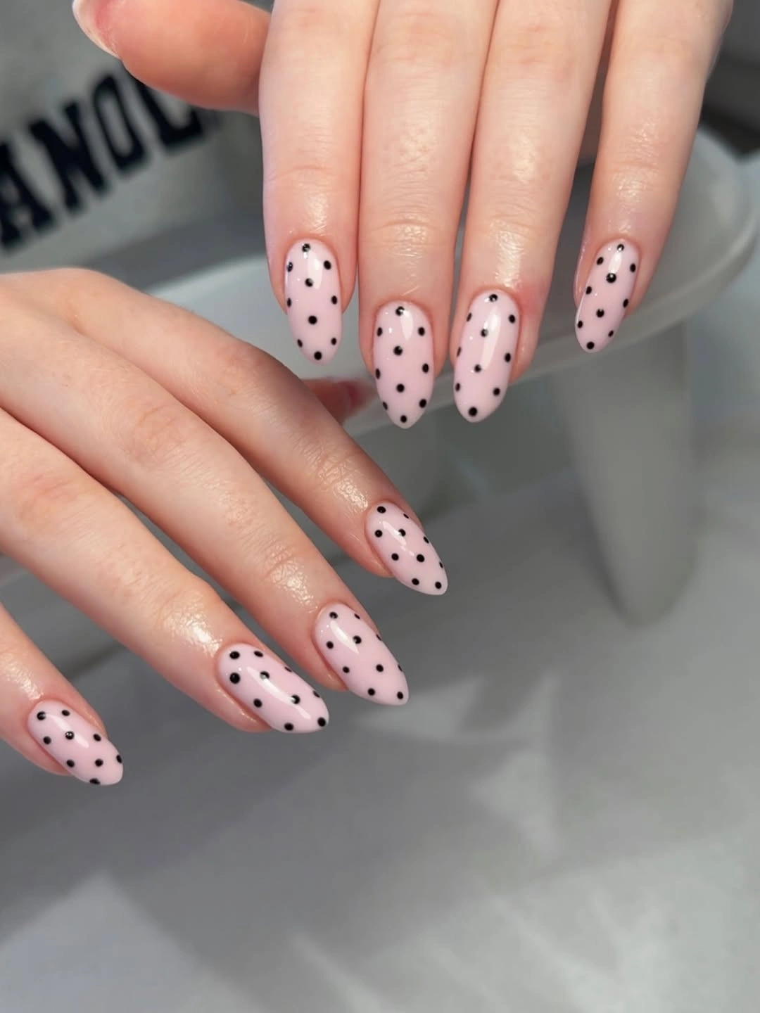 Long blush nails with layered black and white dotted French tips