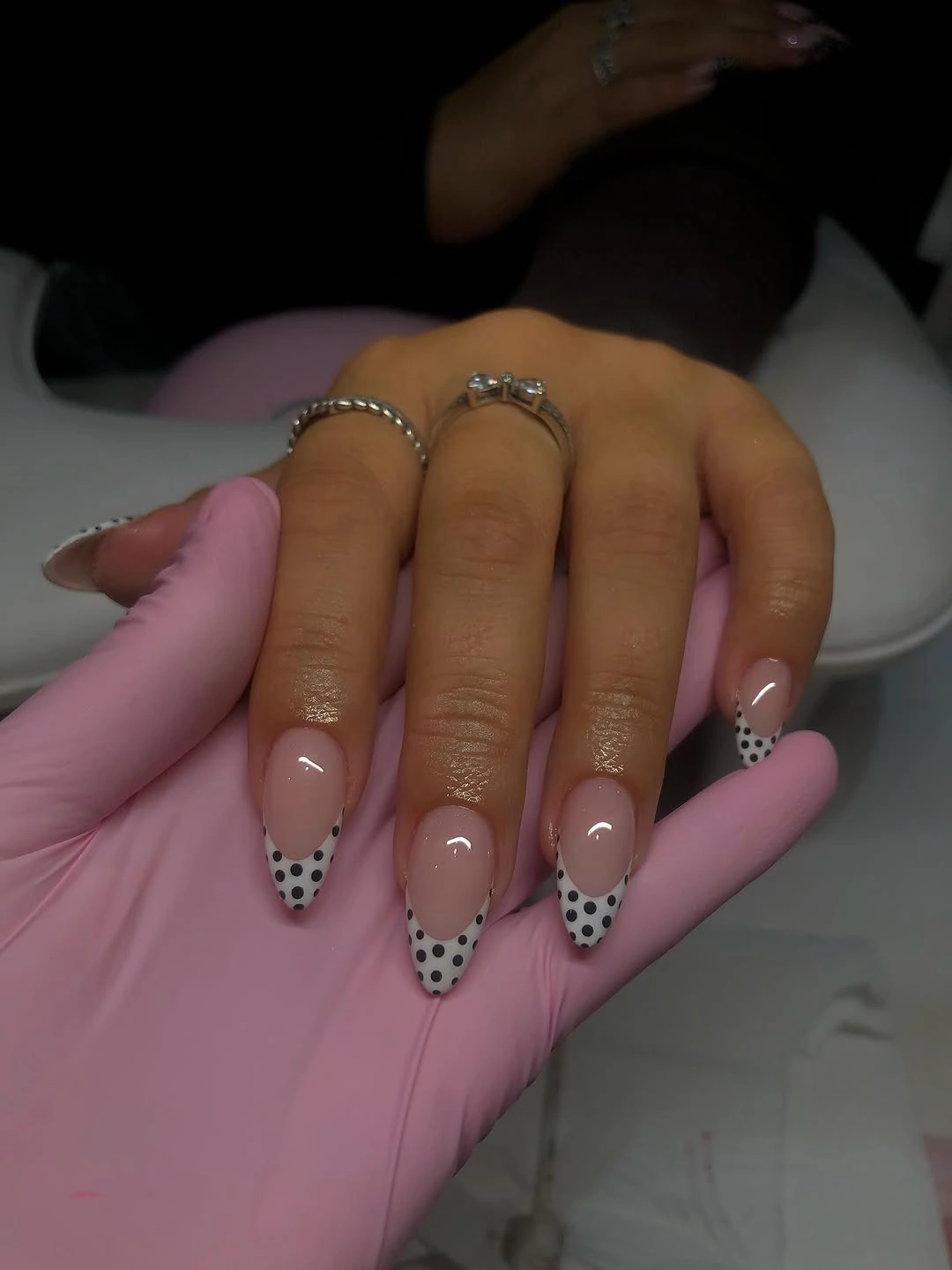 Long pale pink nails with scattered black dots and white spots