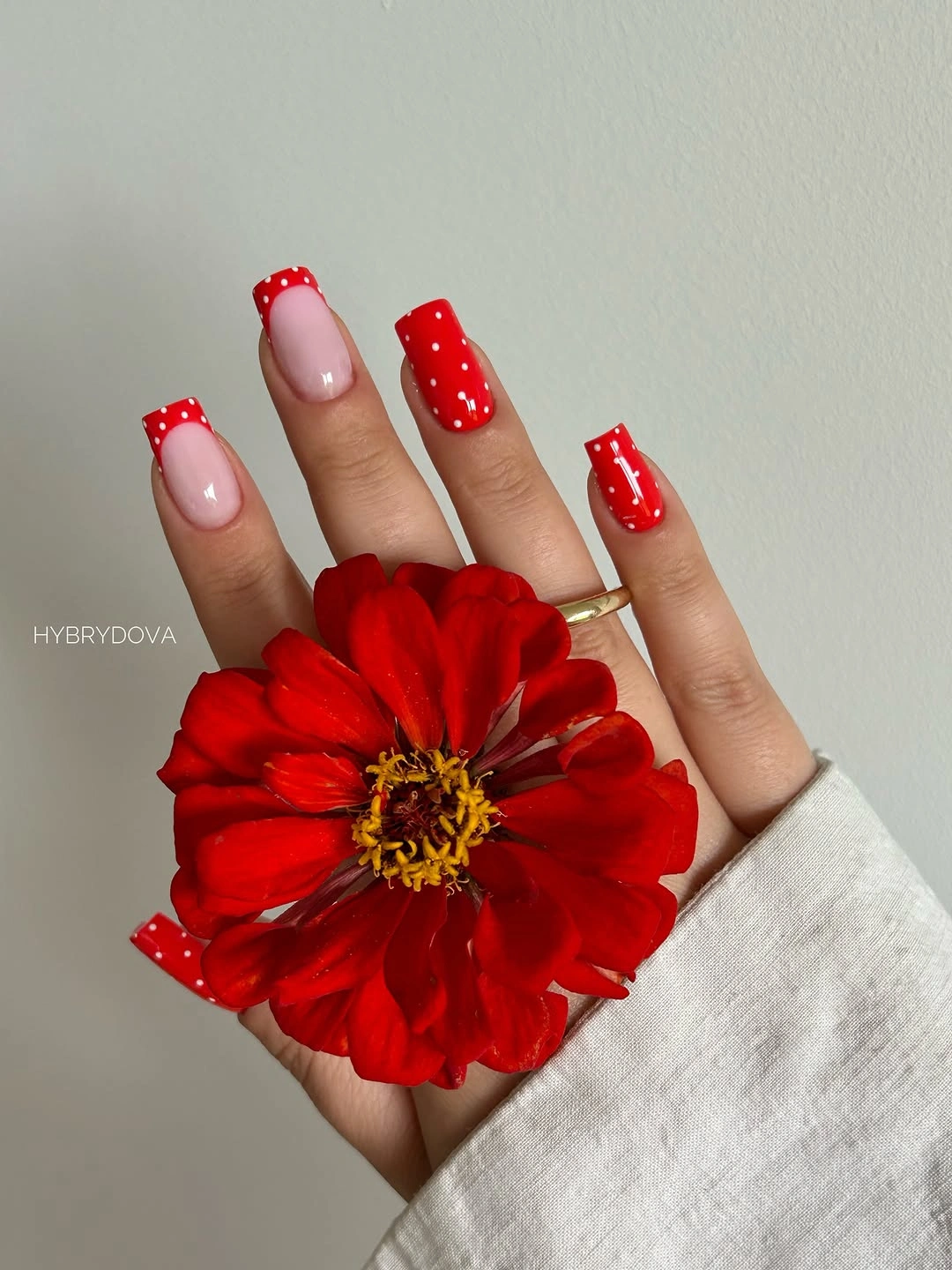 Bright red almond nails with white polka dots and pink accent