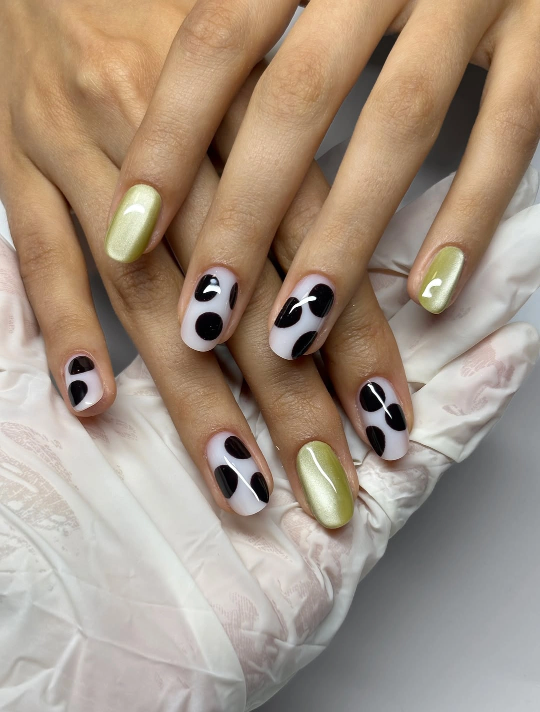 Medium rounded nails with black white spots and pale green solids