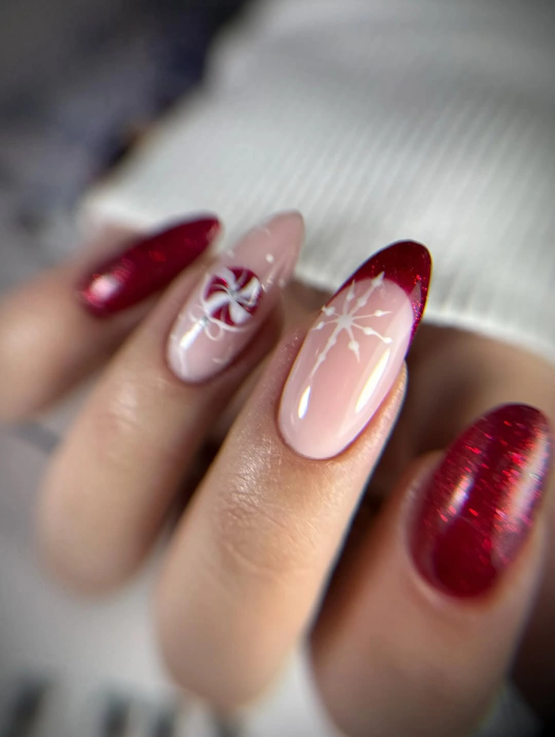 Red glitter and pale pink nails with white winter motifs