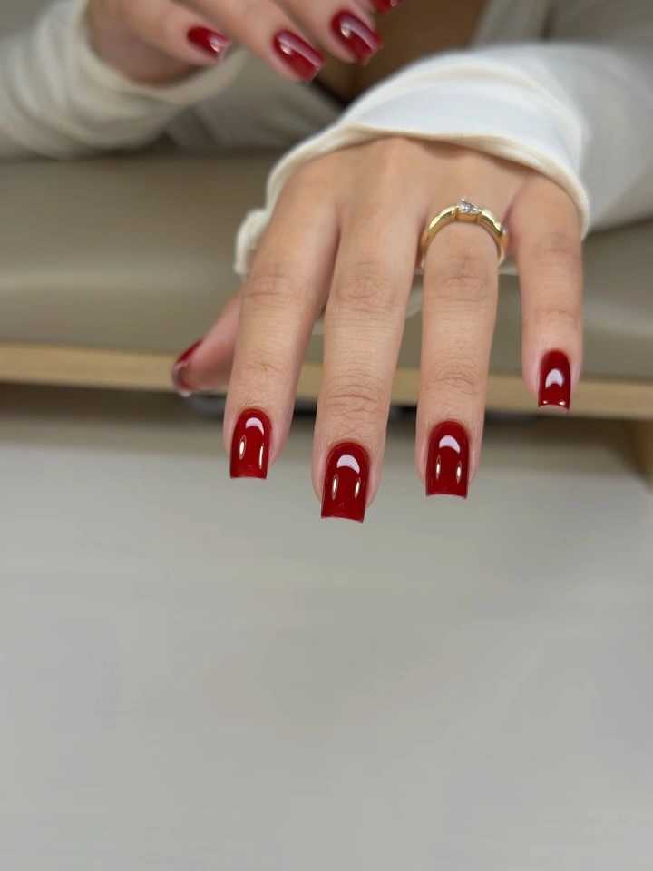 Medium square deep red nails with simple pale curved accents
