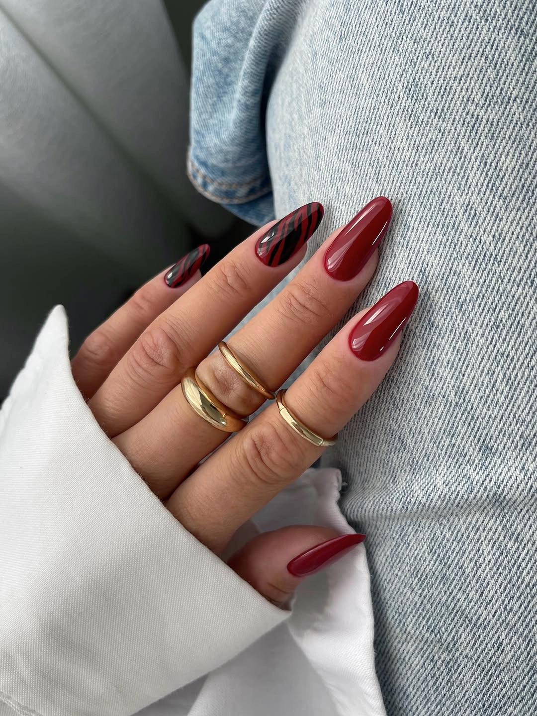 Long burgundy almond nails with dark striped accent nail