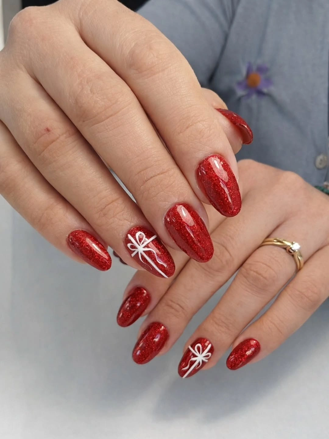 Red glitter nails decorated with white gift bow linework