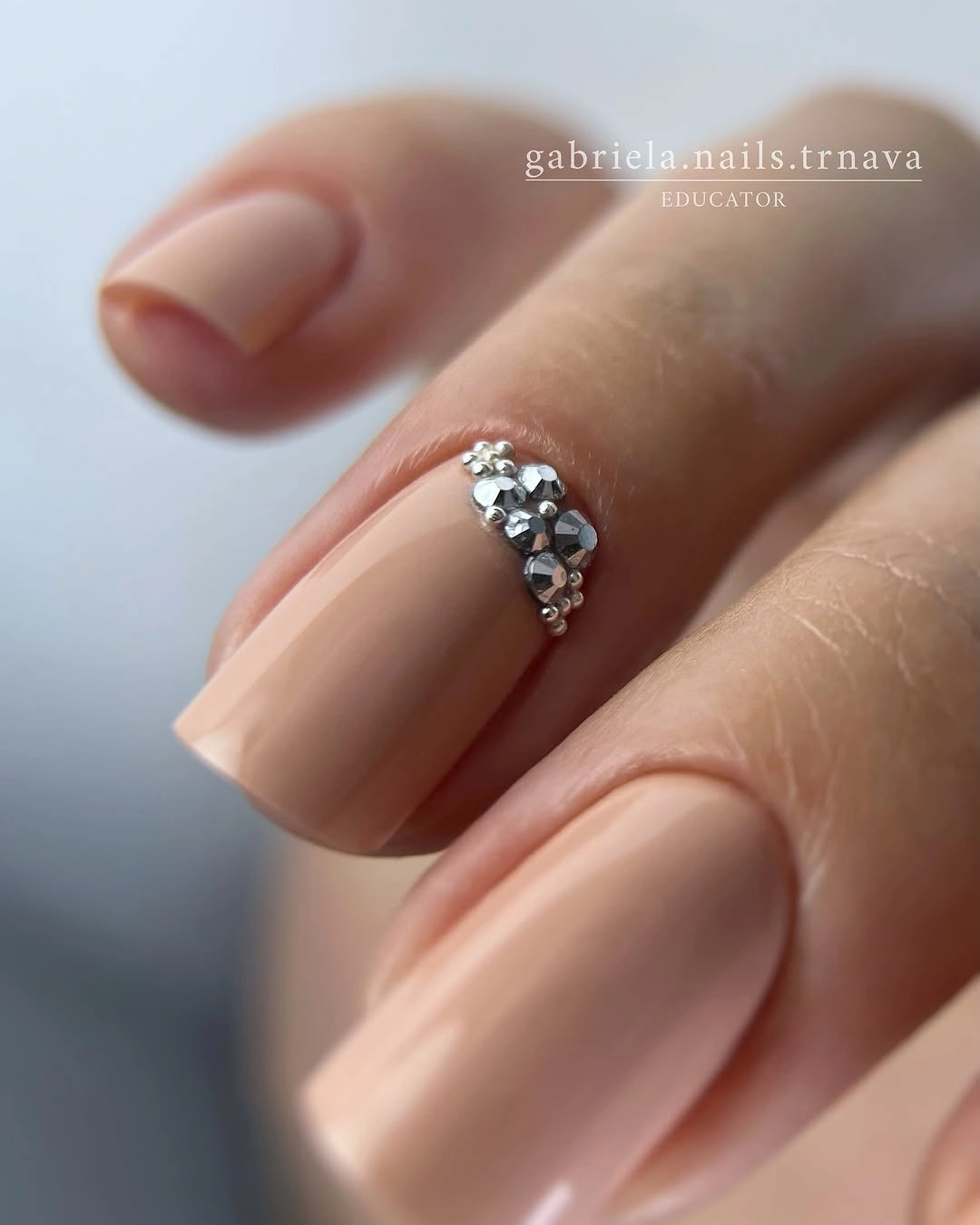 Peach nude short nails with one silver-toned raised accent