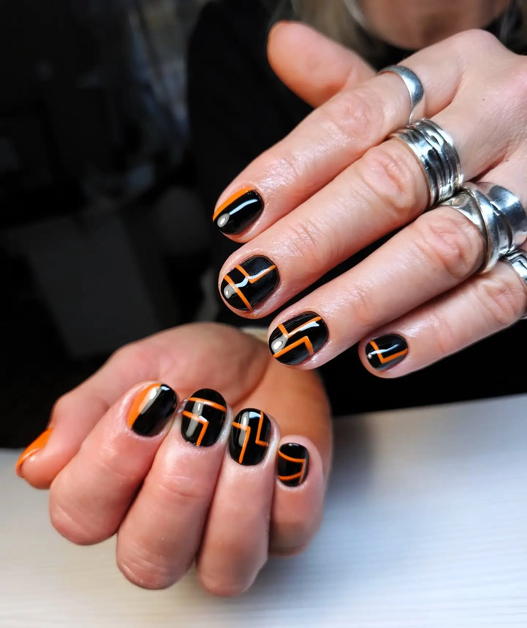 Black short nails with orange line art and small dots