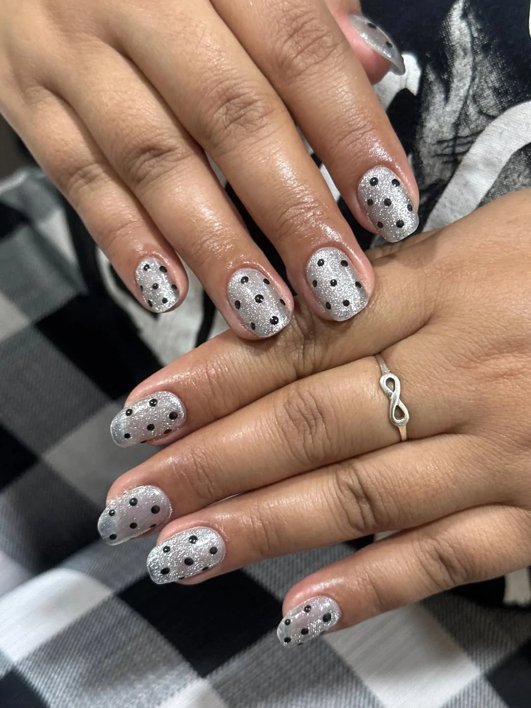 Silver sparkly short nails with repeated black dot pattern