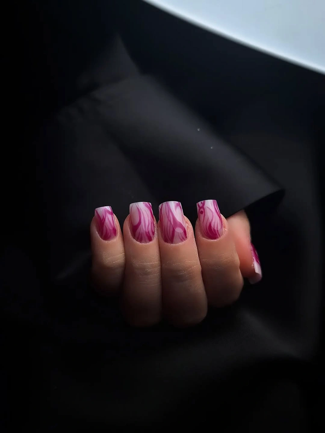 Short square nails with pink marbled strokes over pale base