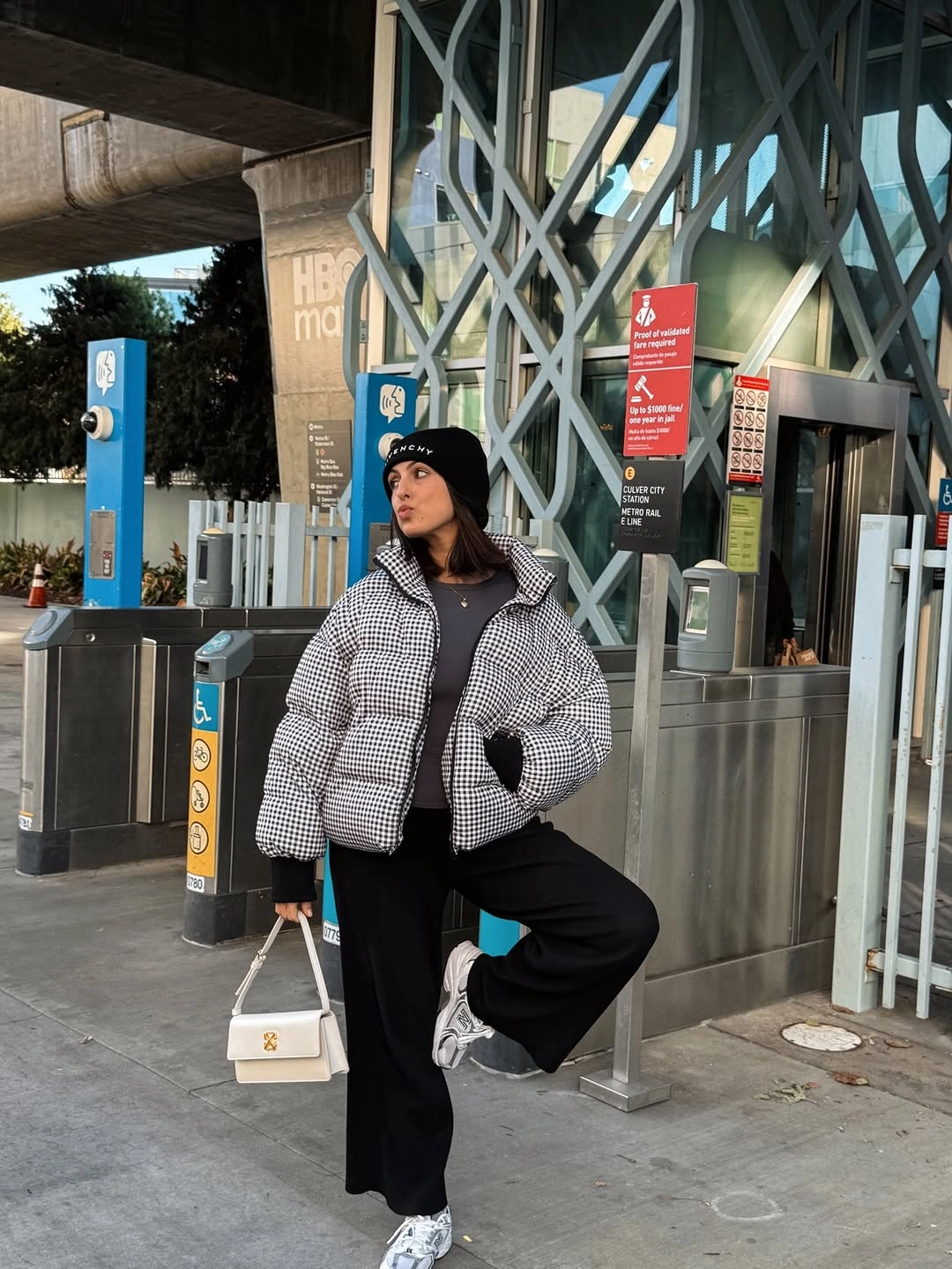 Light gray puffer with black beanie pants white trainers and bag