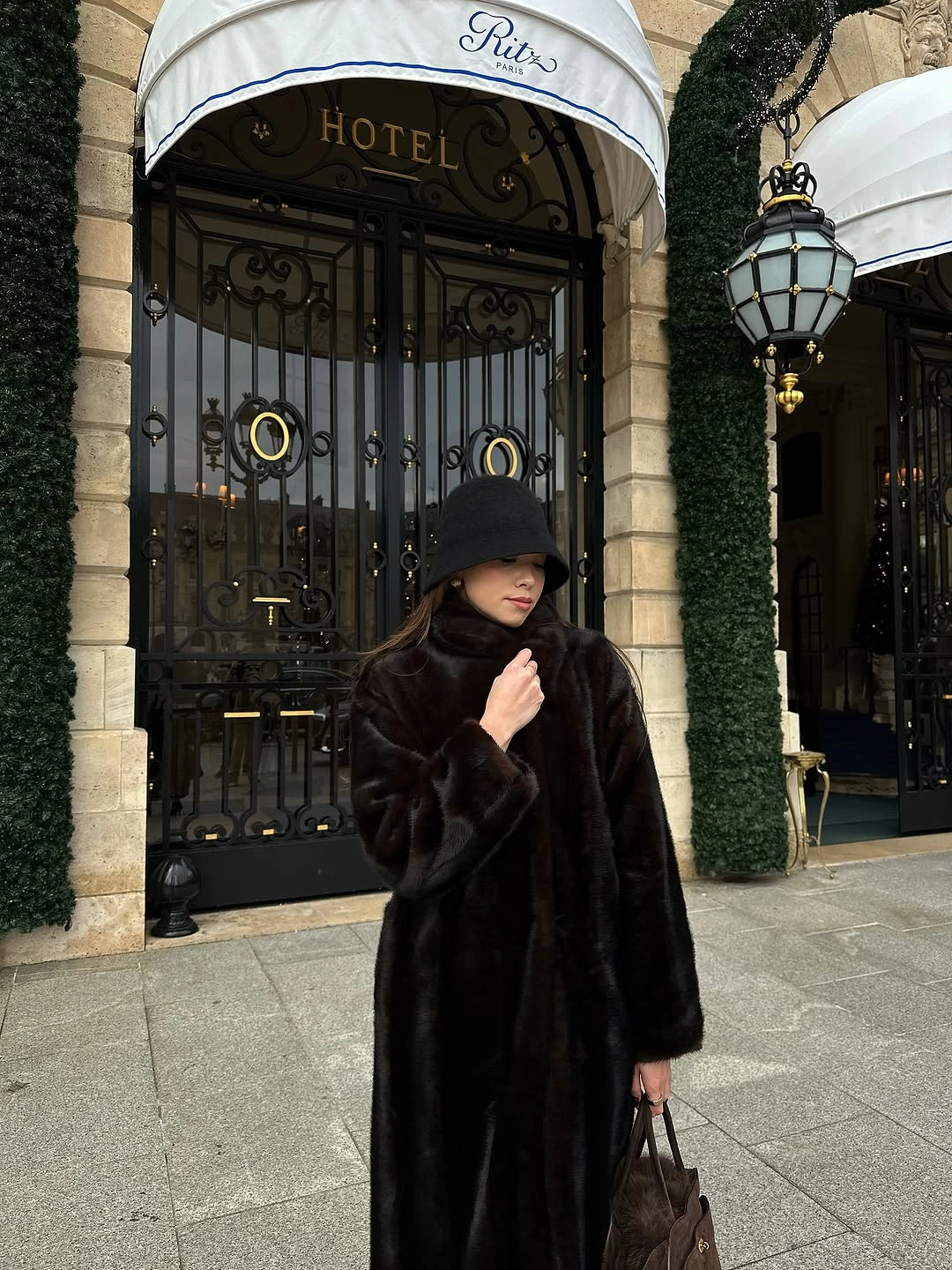 Long black plush coat with rounded black hat and small bag
