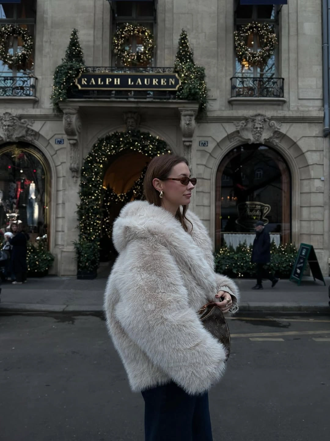 White fuzzy jacket over straight black trousers and sunglasses