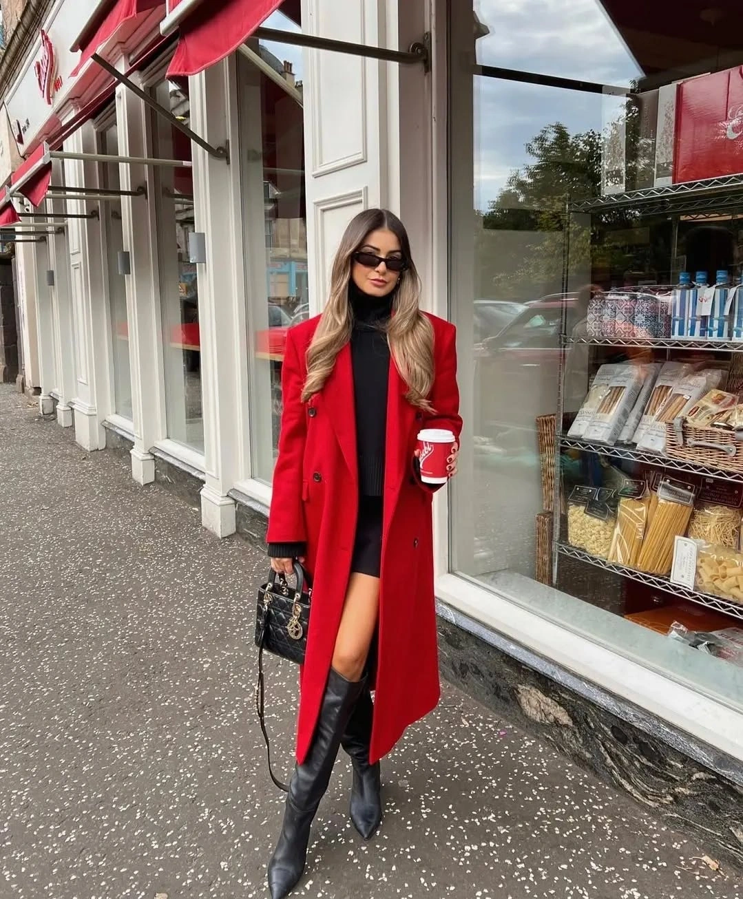 Vivid red long coat with black boots and held bag