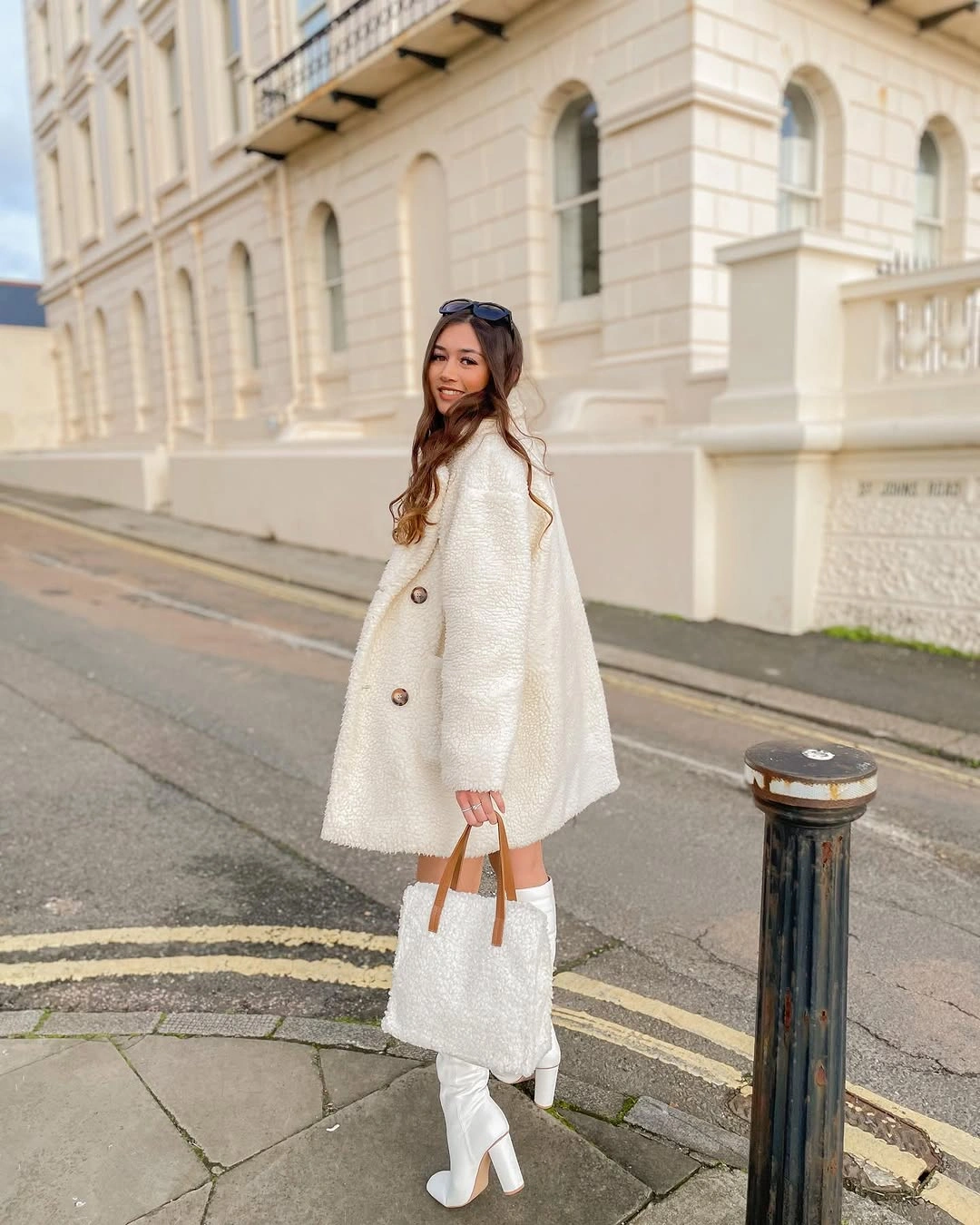 Short white textured-looking coat with white boots and fuzzy bag
