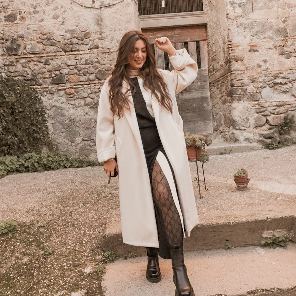 Cream long coat over black outfit with patterned tights