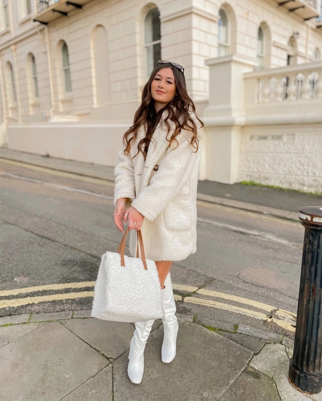 White textured-looking short coat with tall boots and bag
