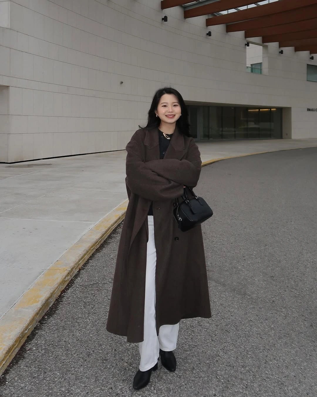 Dark brown long coat over white trousers and black shoes