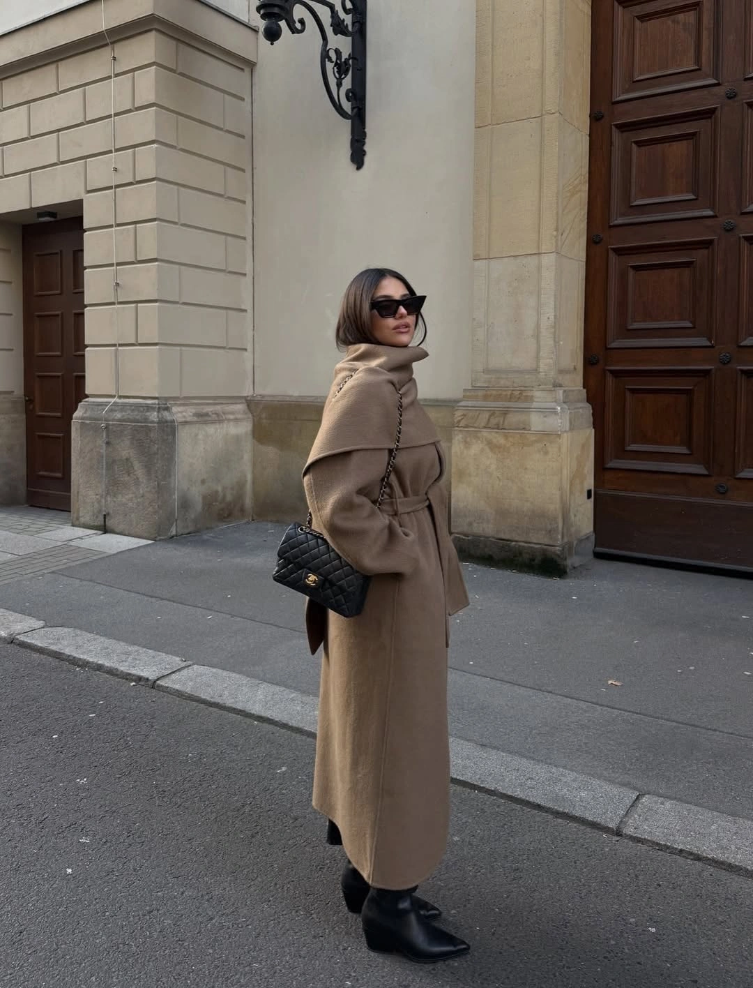 Camel brown belted long coat with black boots and bag