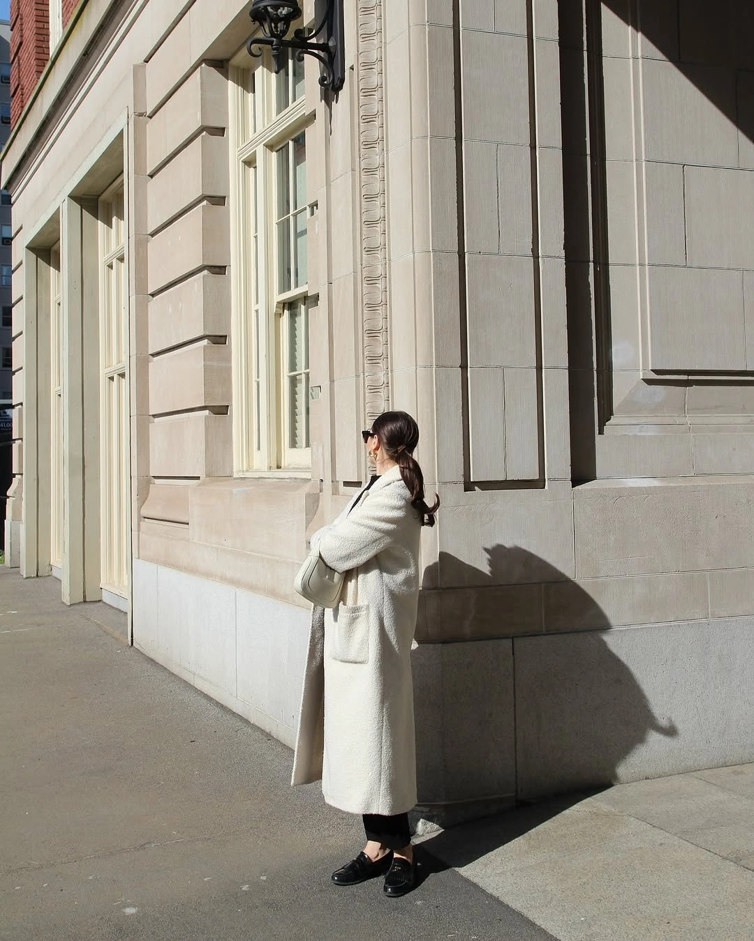 White long coat over dark lower clothing and black shoes