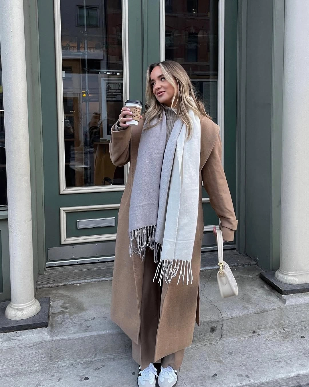 Camel brown long coat with pale scarf and white sneakers