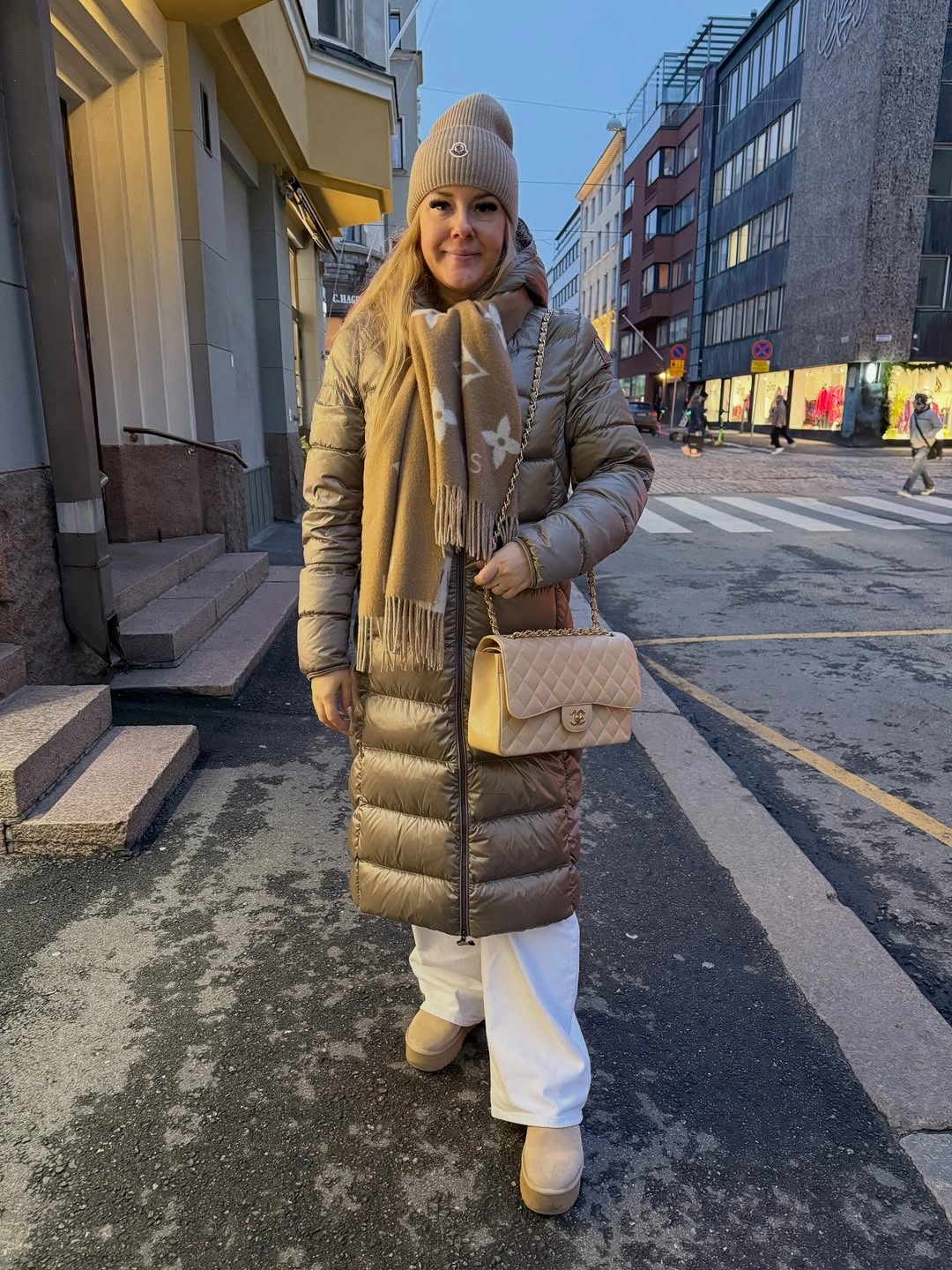 Long taupe padded coat with beige scarf and white pants