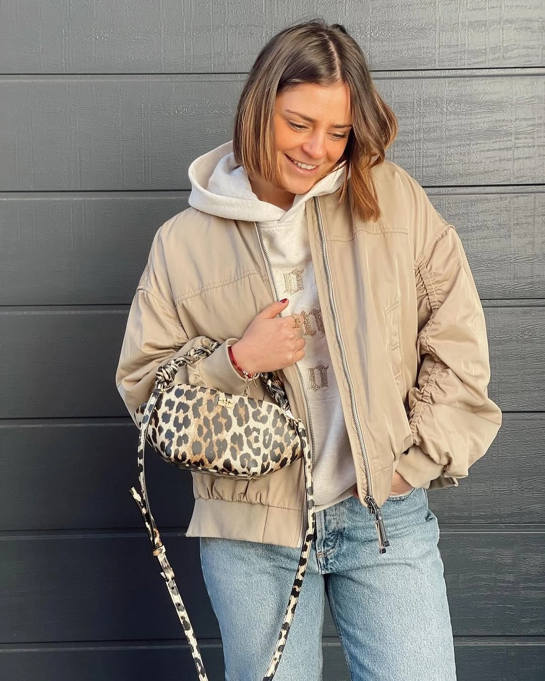 Beige padded-looking jacket with white hoodie and light denim