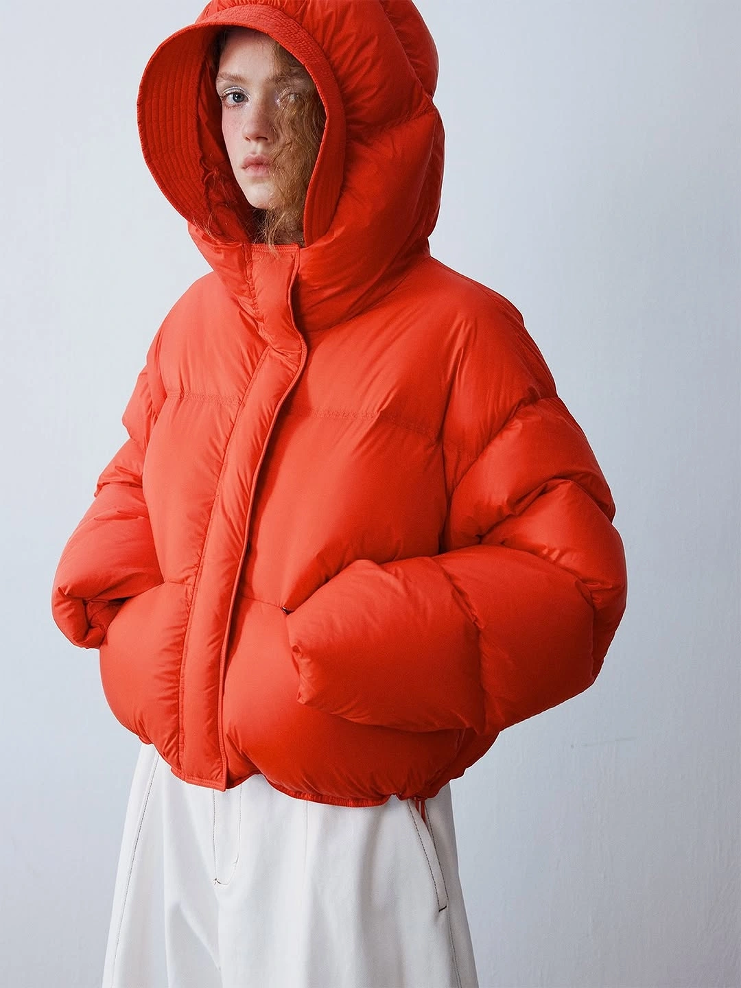 Red-orange hooded padded jacket over a white lower piece