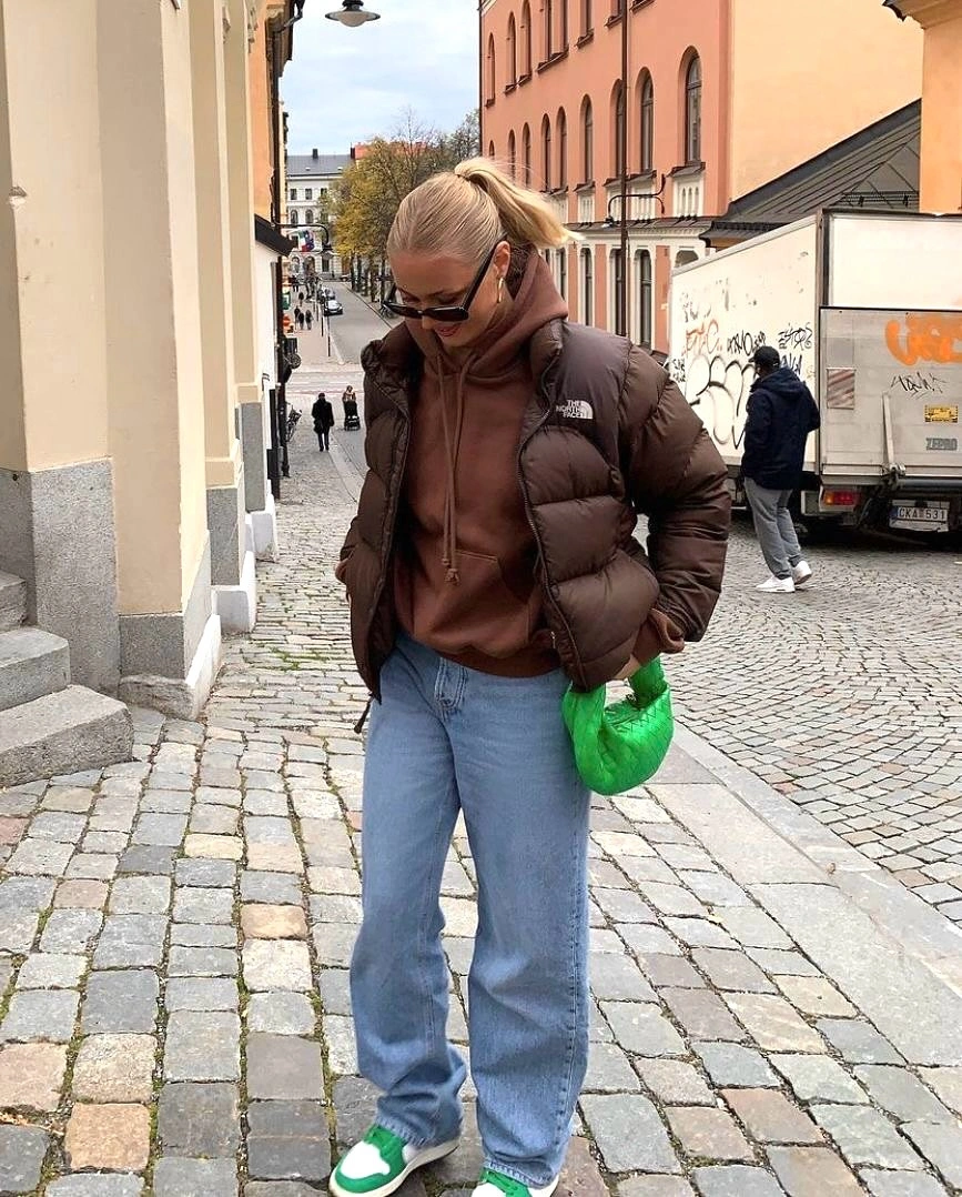 Brown padded vest over hoodie with green bag and sneakers