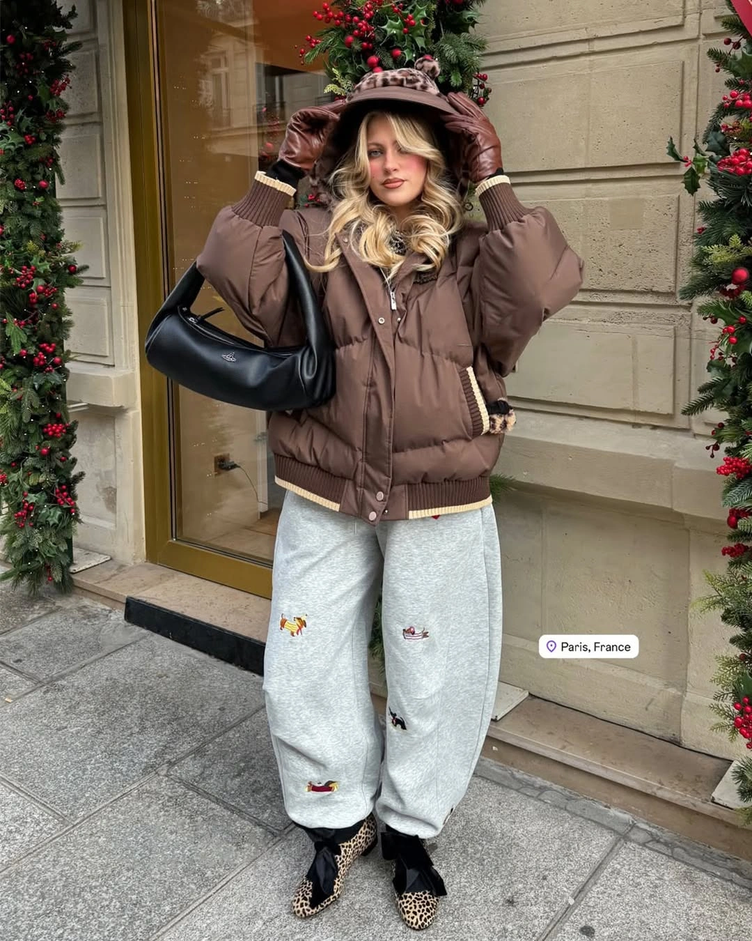 Brown cropped hooded padded jacket with gray sweatpants and black bag