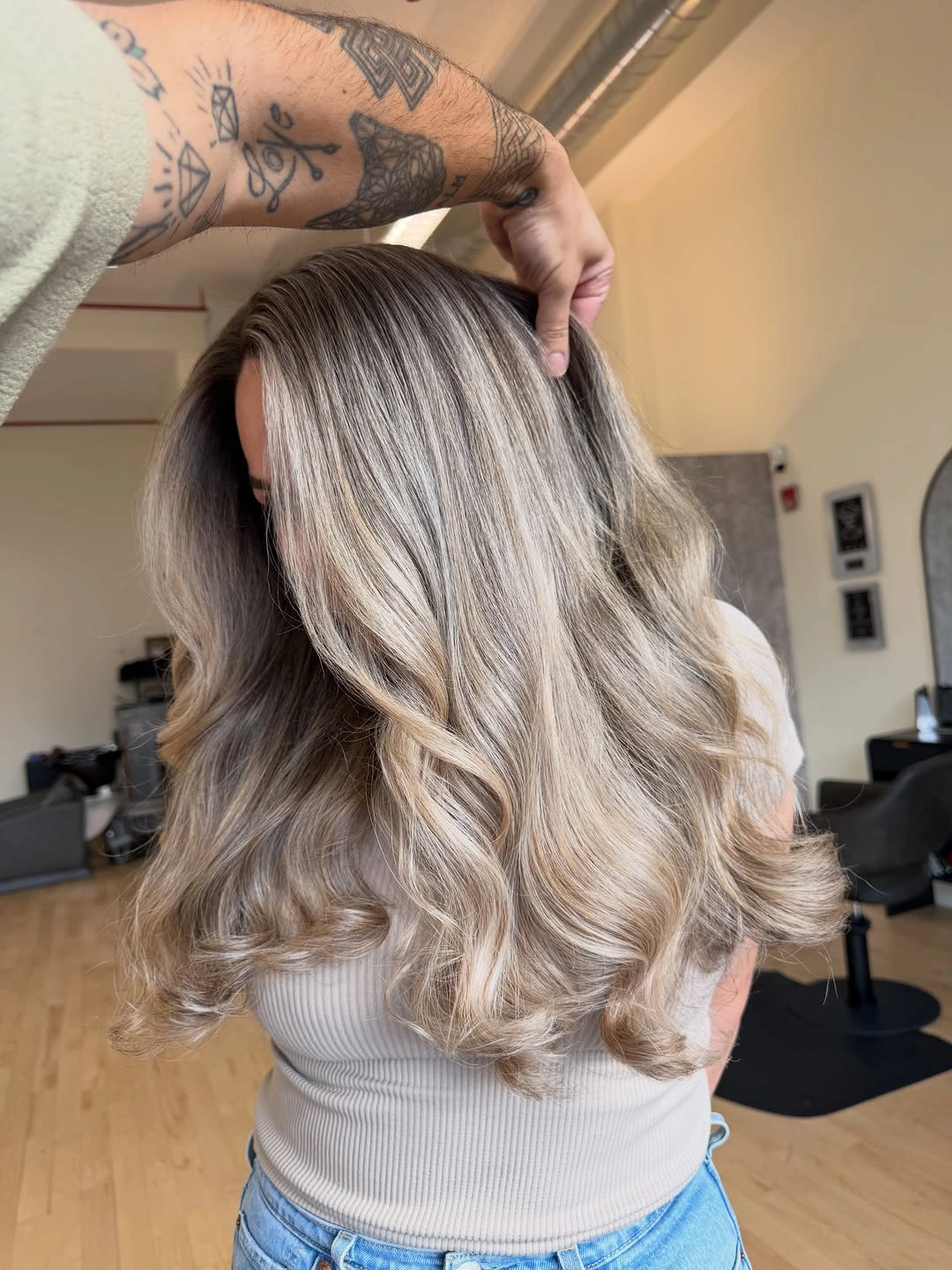 Long ash beige blonde wavy layers from behind