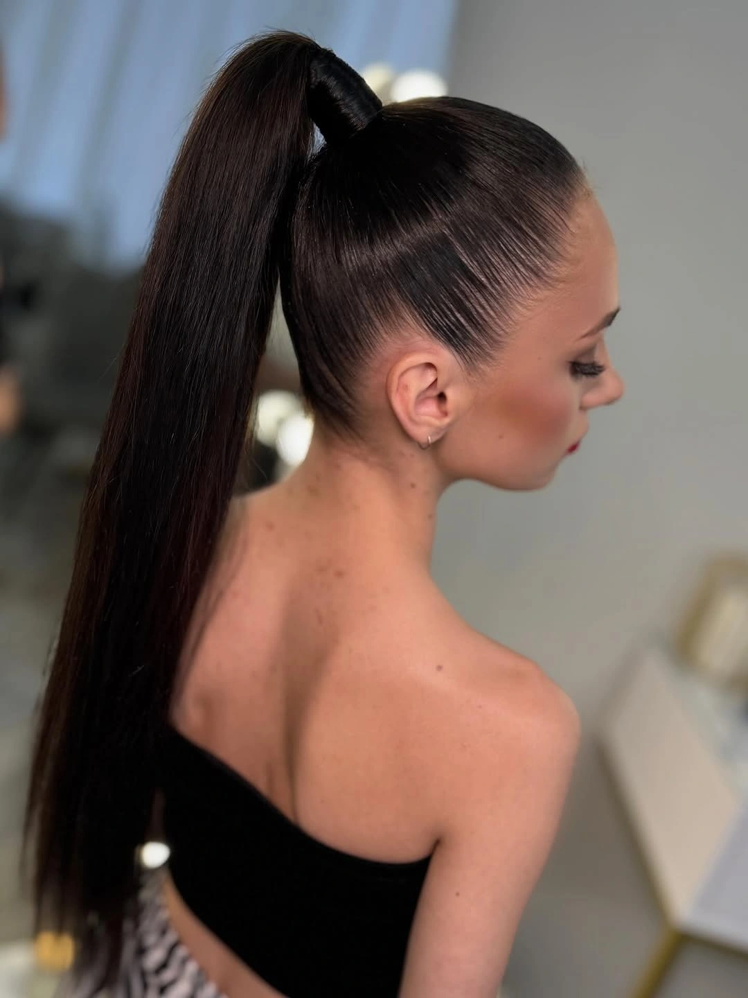 High sleek dark ponytail shown in profile