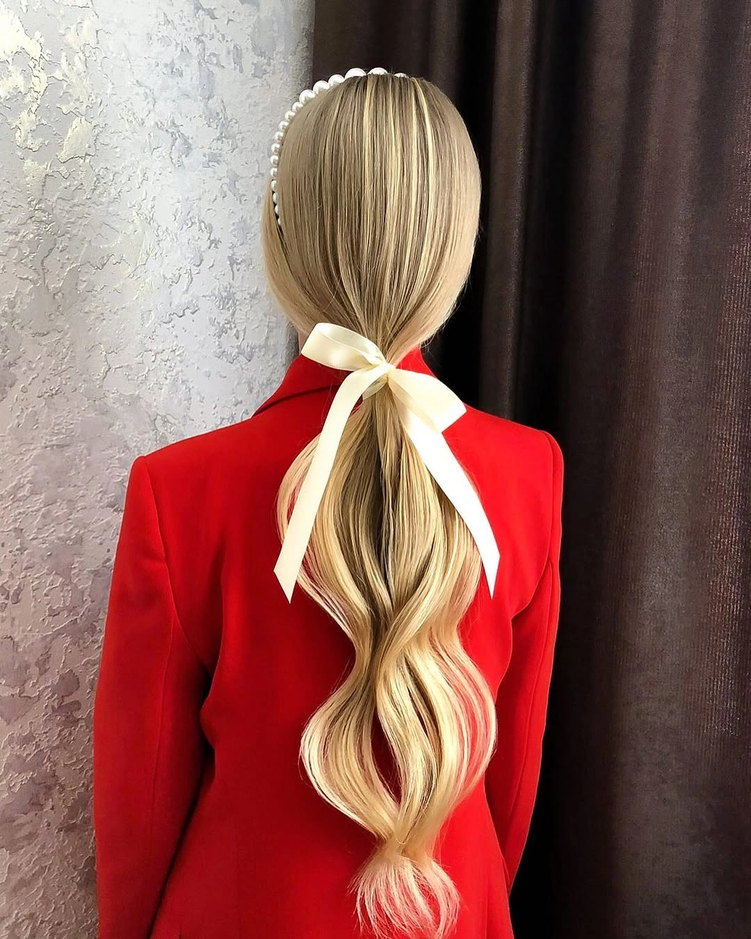 Blonde low ponytail with white ribbon and red blazer