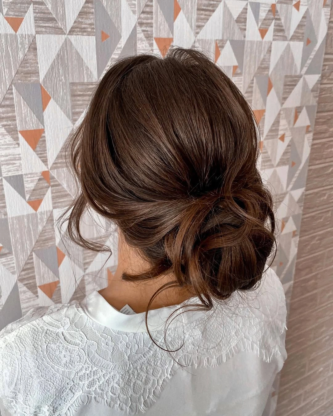 Warm brown low bun with loose back pieces