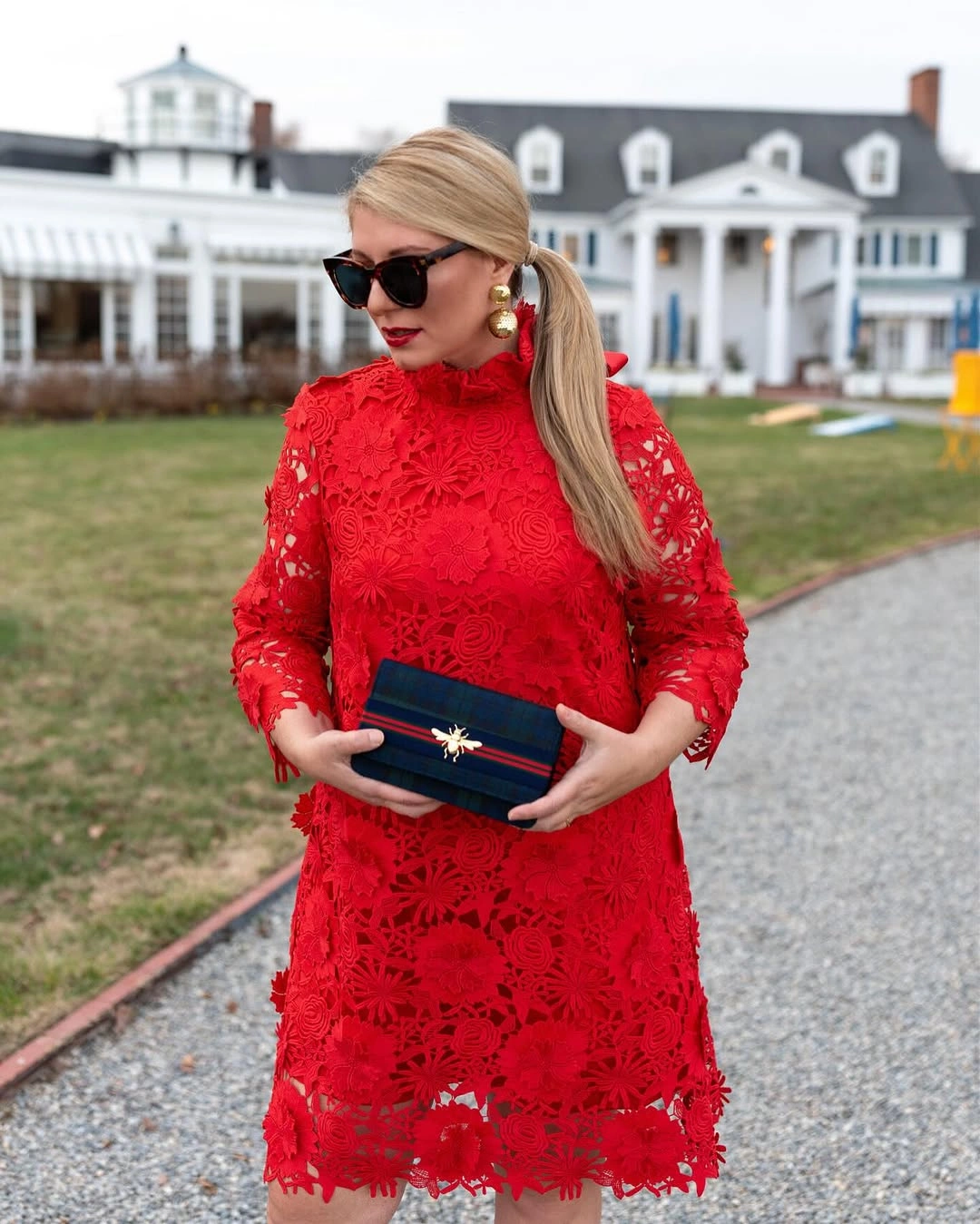 Red lace high-neck dress with dark clutch and earrings