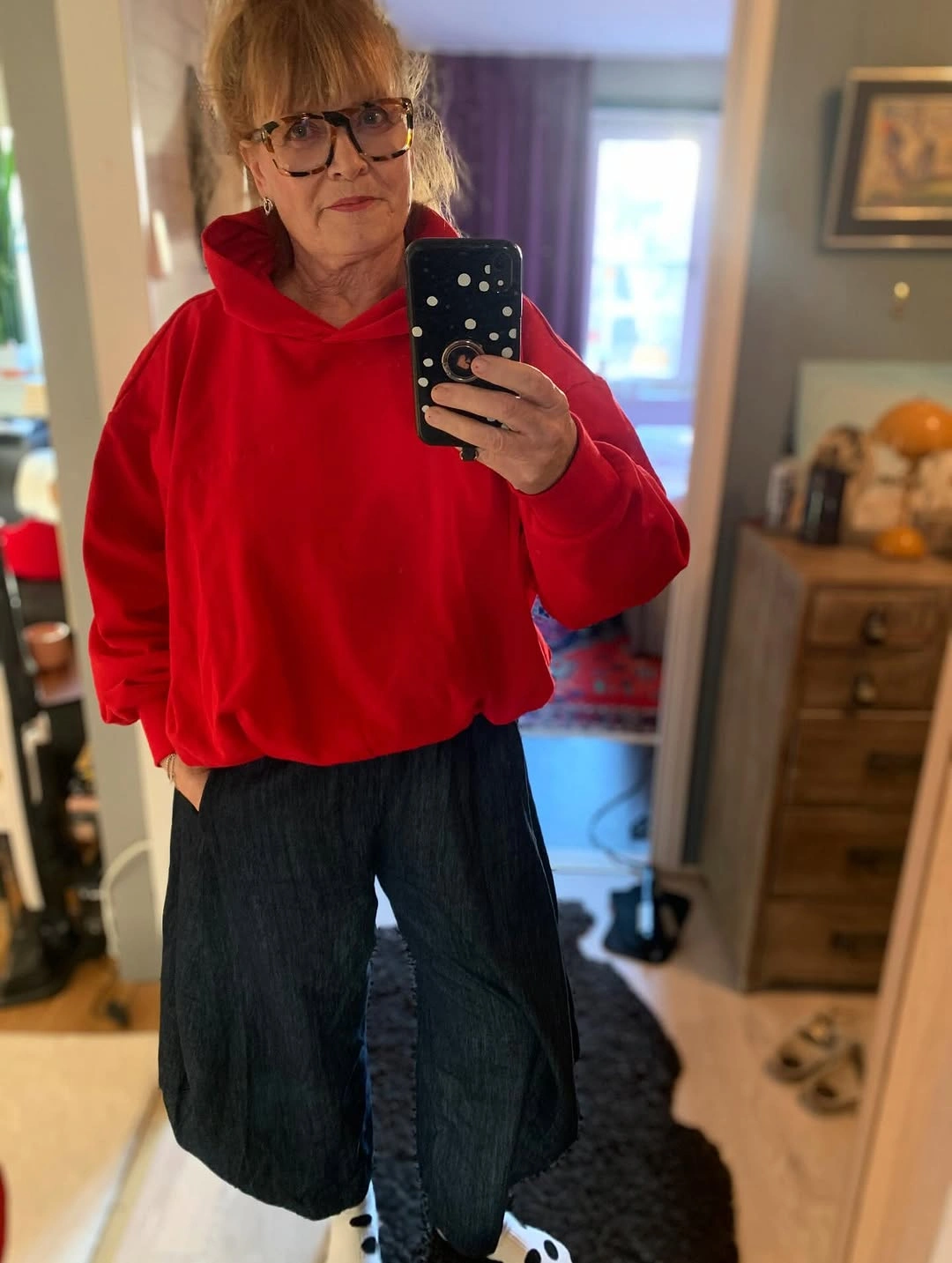 Red hoodie with dark wide cropped pants and patterned socks