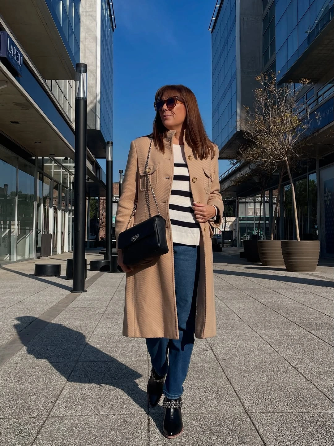 Camel coat with striped sweater, jeans and black accessories