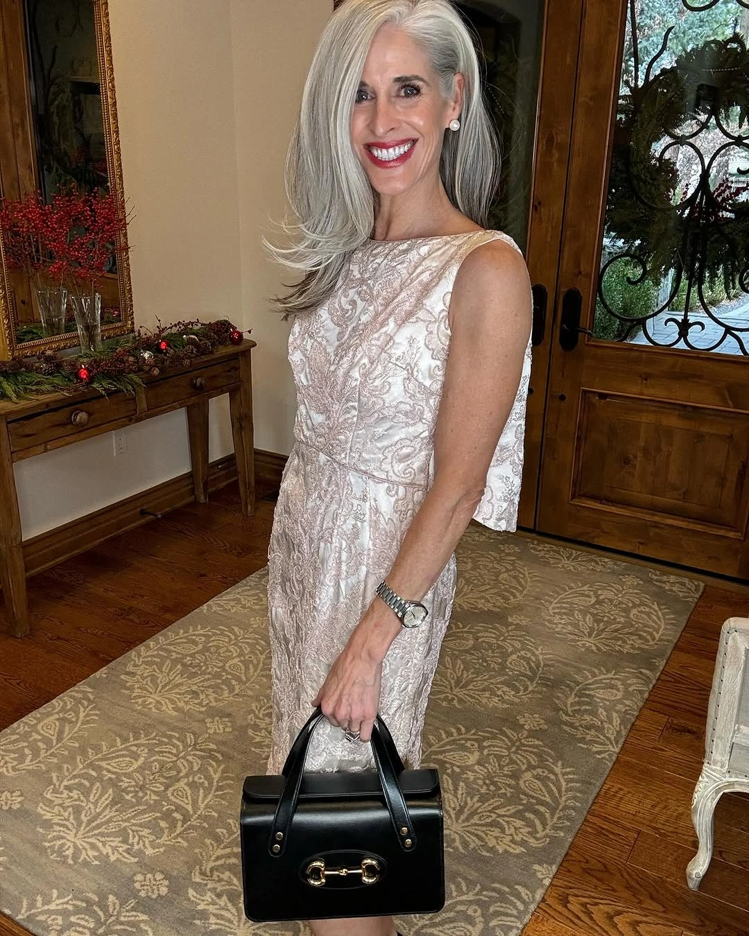 Pale patterned sleeveless dress with defined waist and black handbag