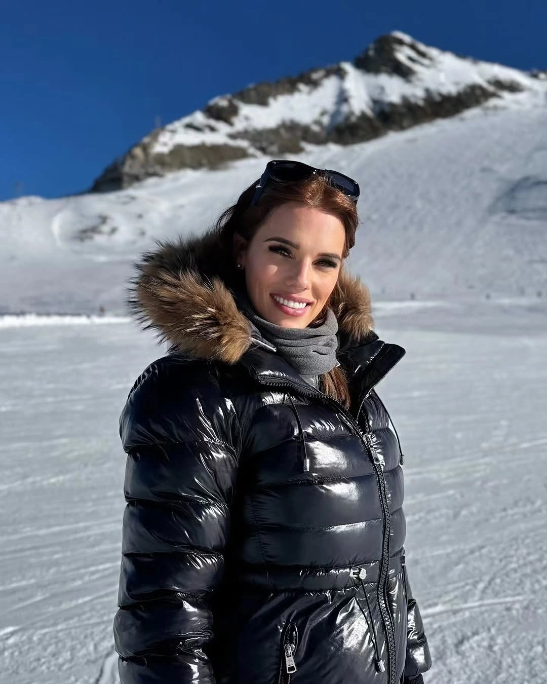 Shiny black puffer jacket with gray scarf and fur-like hood trim