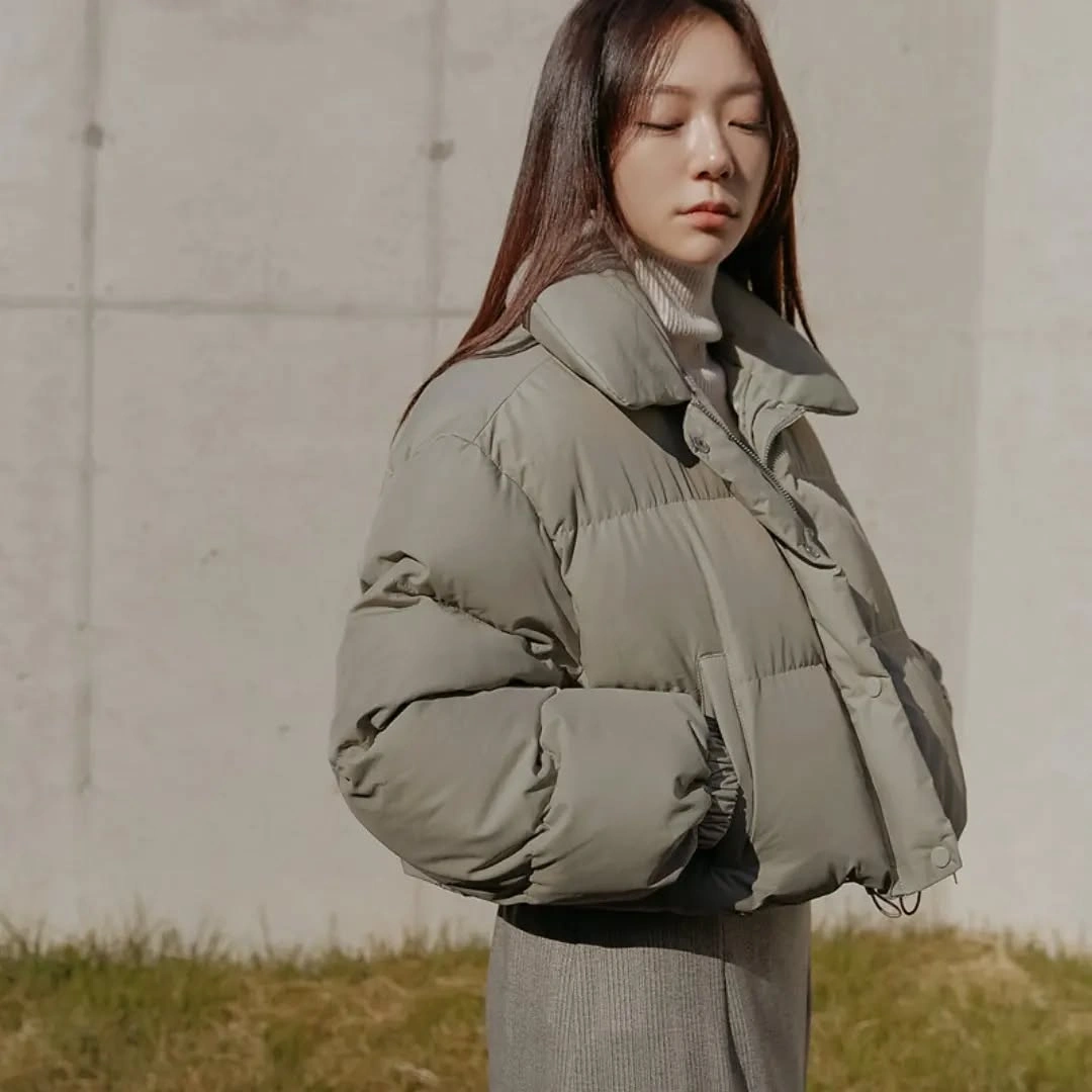 Muted green cropped puffer over pale ribbed turtleneck and long gray layer