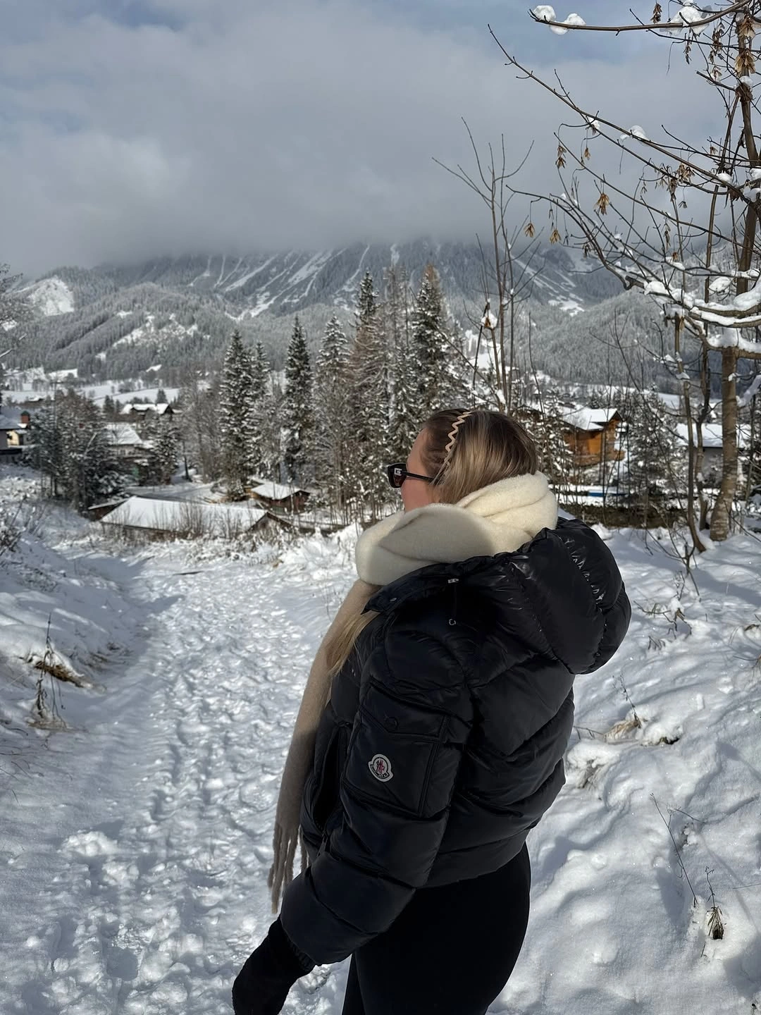 Black hooded puffer with pale scarf on snowy path