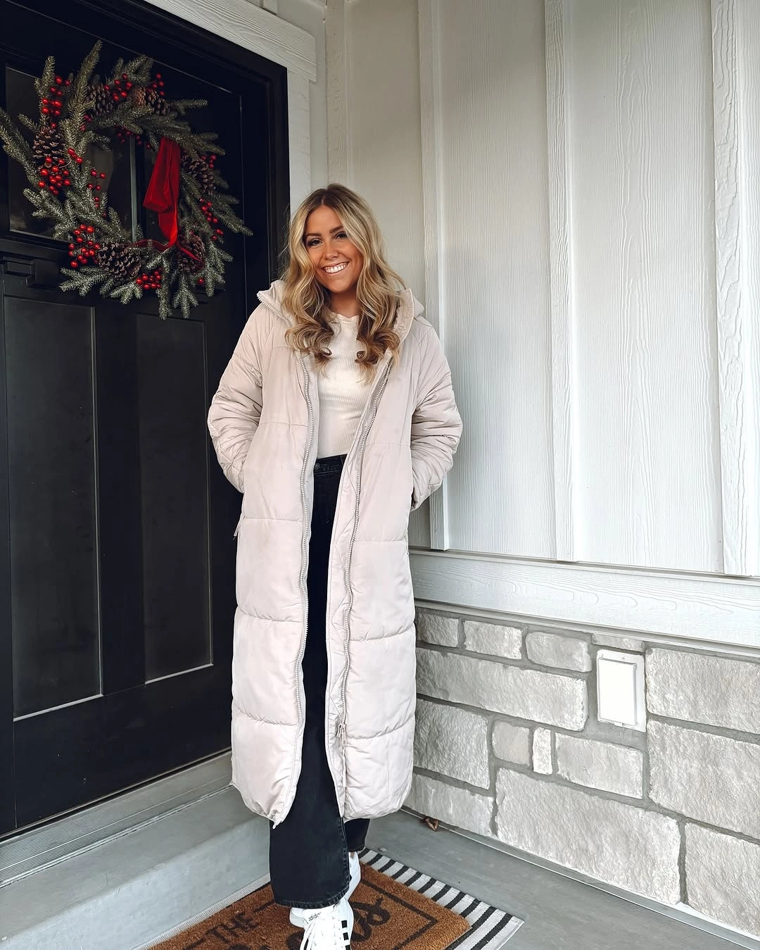 Pale long puffer coat over dark column and sneakers