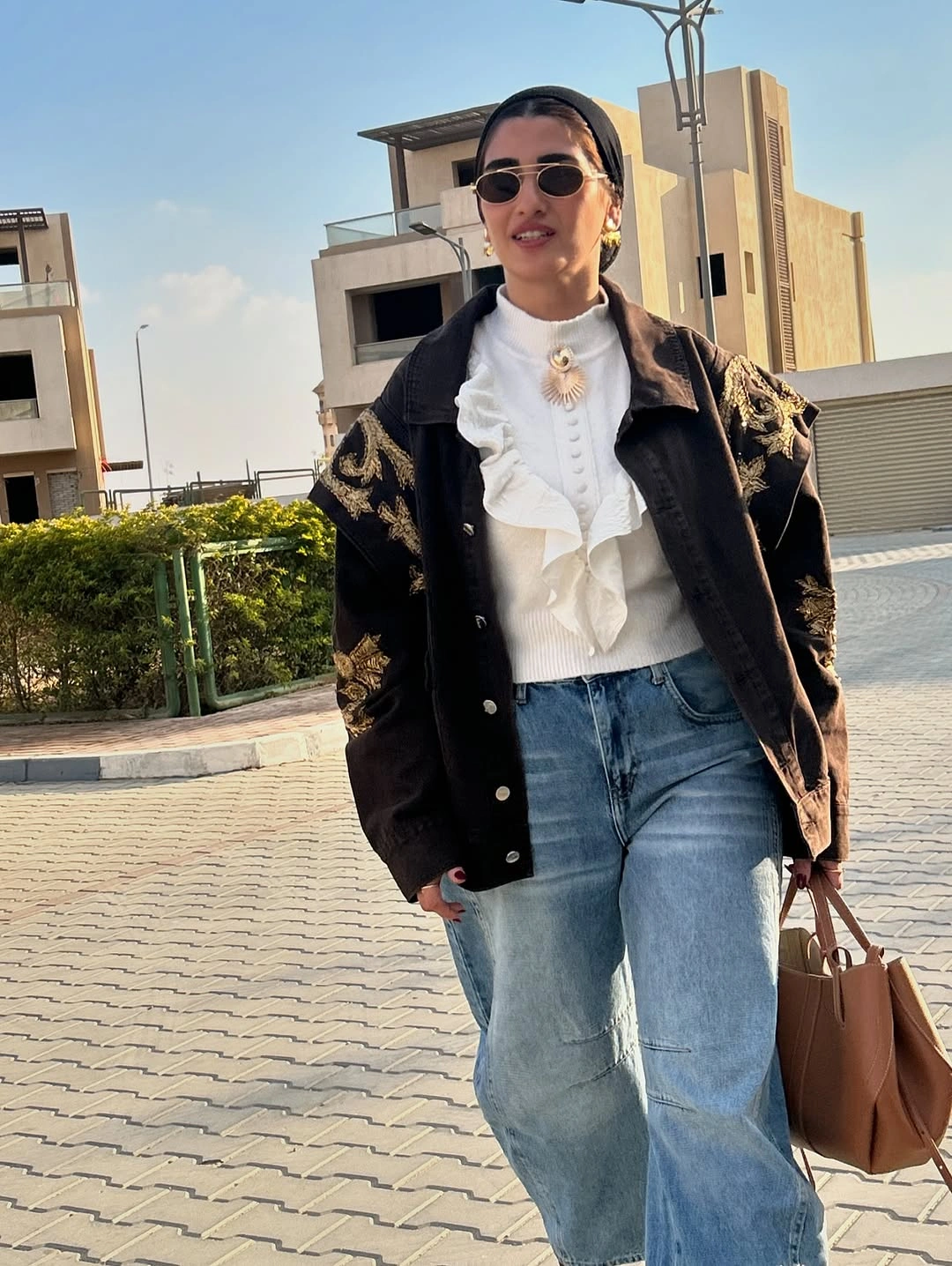 Dark detailed jacket with ruffled white blouse and jeans
