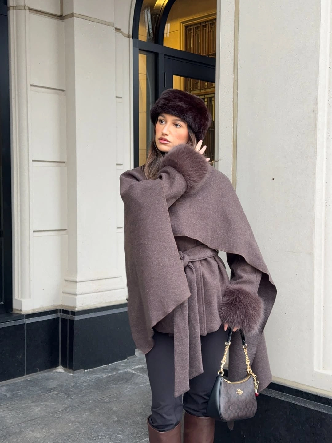 Mauve-brown cape-like layer with belt and dark trousers