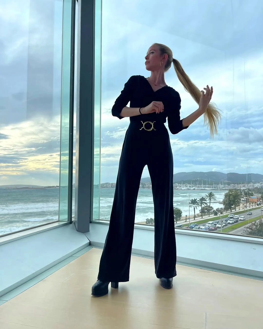 Fitted black top with wide trousers and circular belt detail