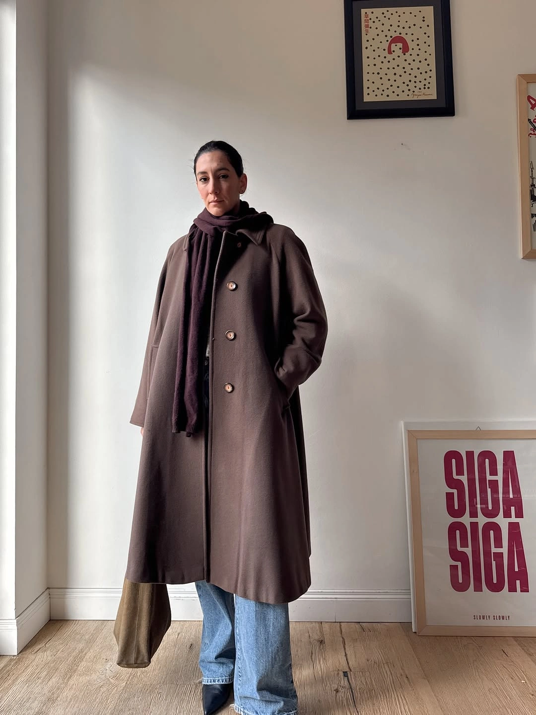 Long brown coat and scarf layered over relaxed blue jeans
