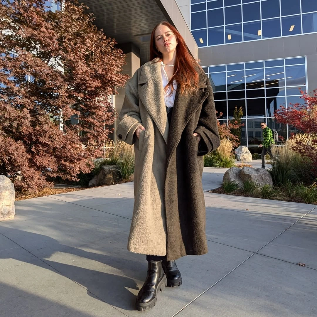 Long taupe coat with broad lapels and tall black boots