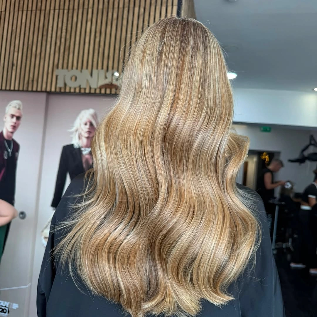 Long beige-blonde S-waves with deeper roots and glossy finish