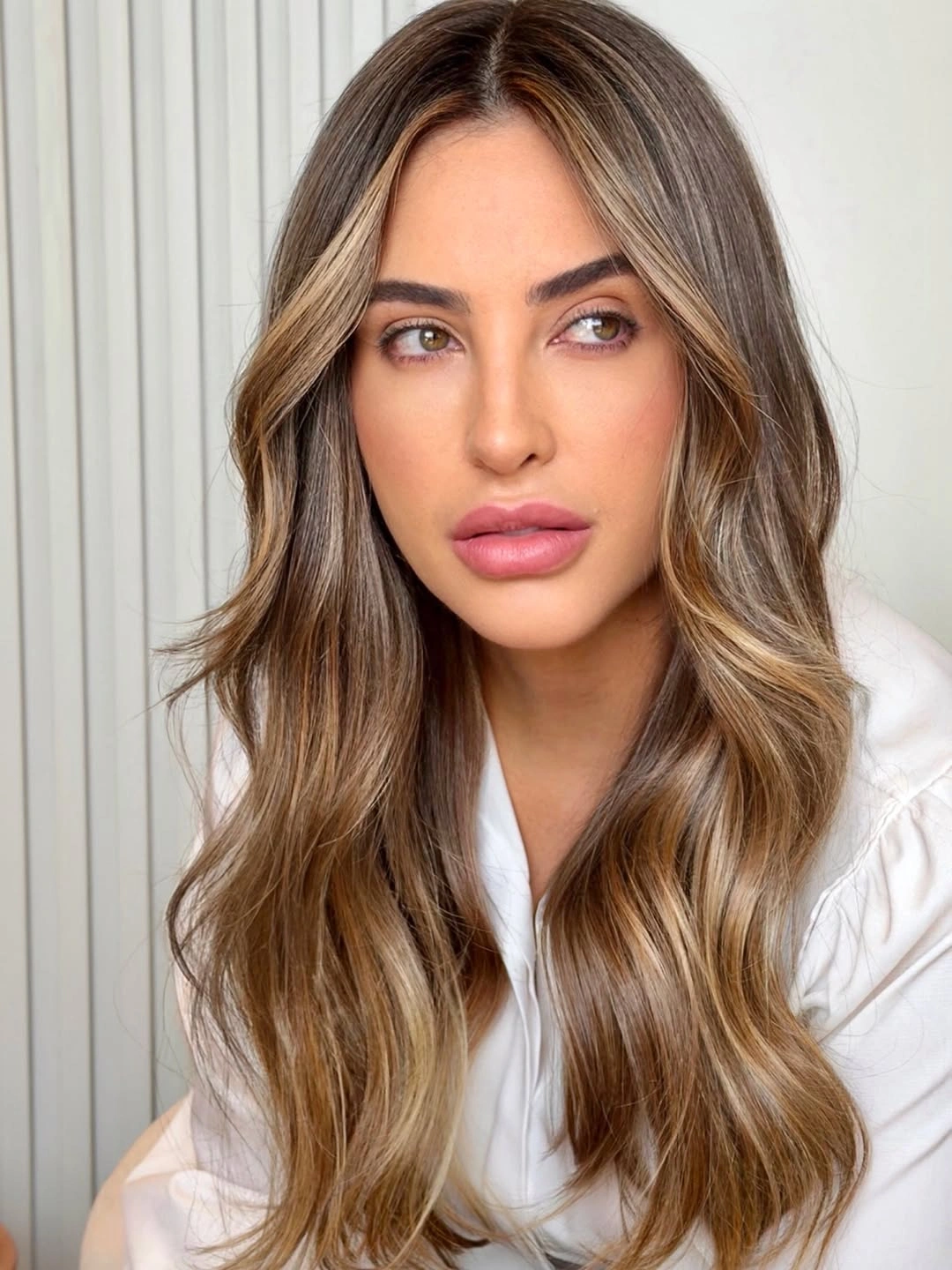 Long brown waves with blended beige highlights around face and lengths