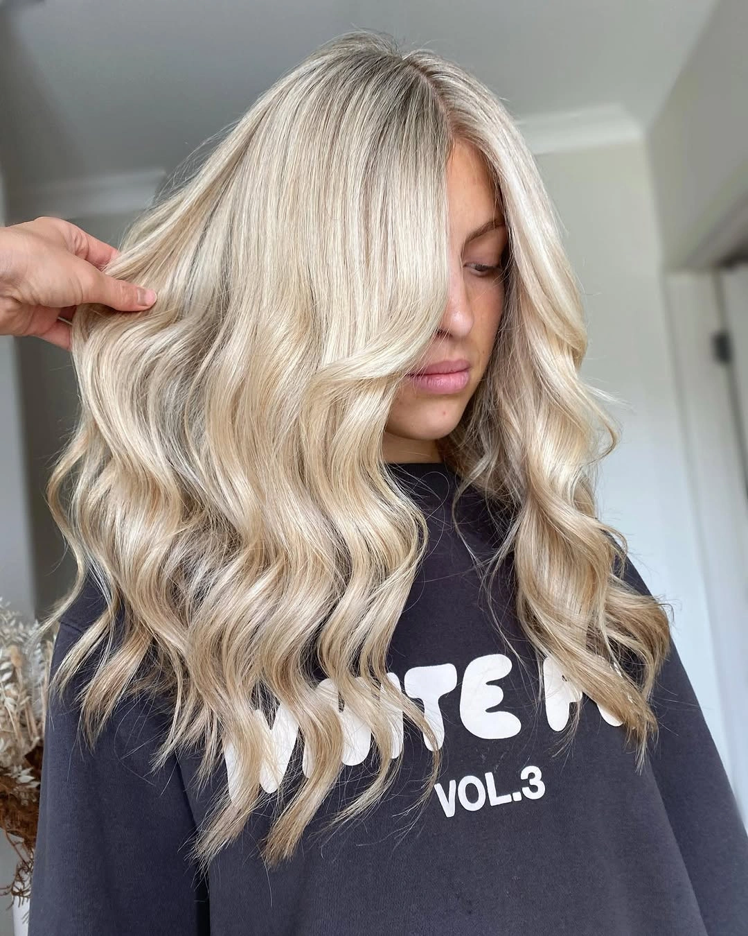 Medium-long wavy blonde with creamy front sweep and beige root