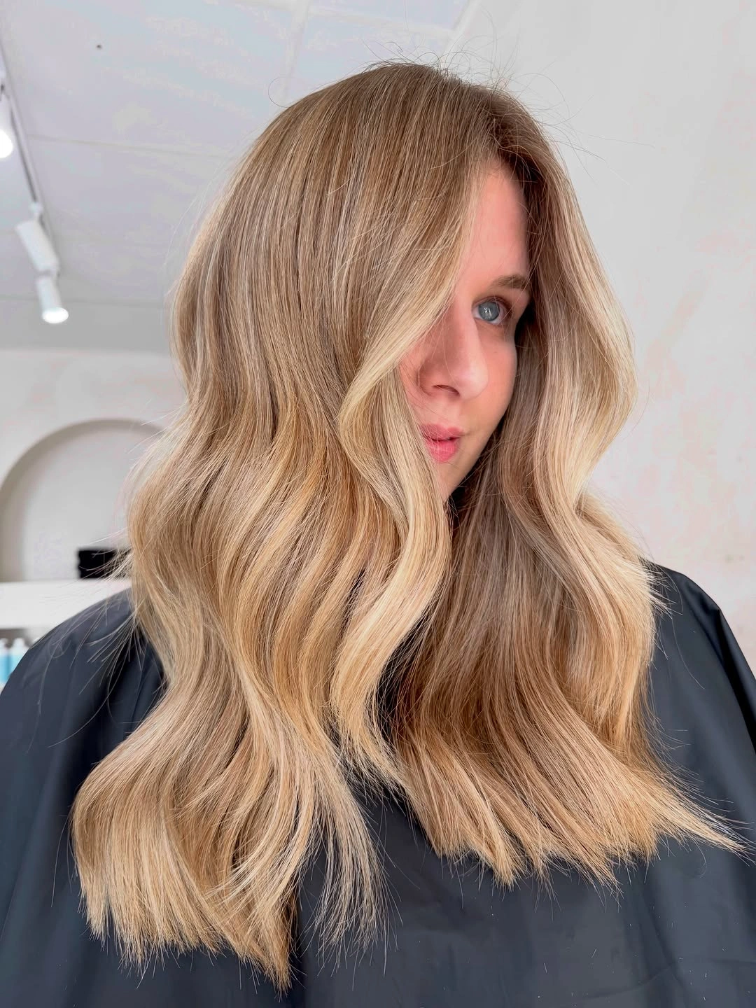 Medium-long honey beige blonde waves with soft side part